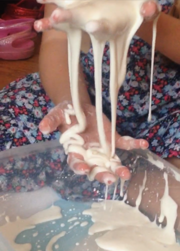 Child's hands holding ooblek - a homeschool science experiment that makes a fluid that changes shape with force