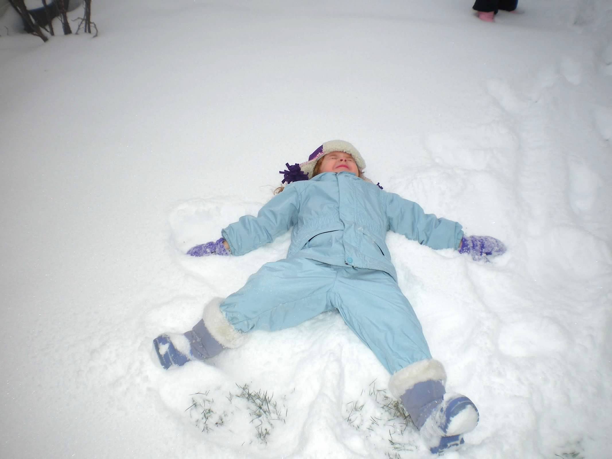 child making a snow angel having winter homeschool fun